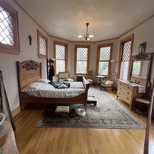 a bedroom with a bed, dressers, and a chair