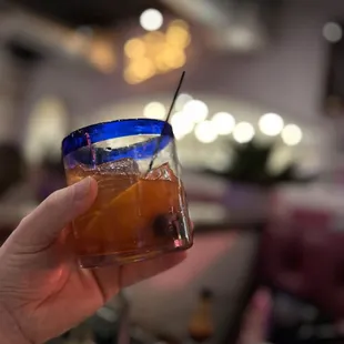 a hand holding a blue glass with a straw