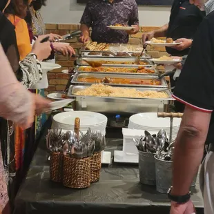 a group of people standing around a buffet table