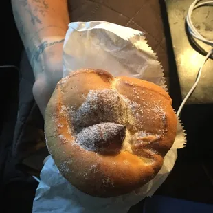 a person holding a donut with powdered sugar