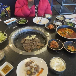 Salad, beef brisket, garlic, rice, radish, kimchi, pork shoulder, cucumber, jalapeños, tteokbokki (rice cake dish)