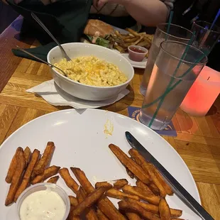 a plate of fries and a bowl of macaroni and cheese