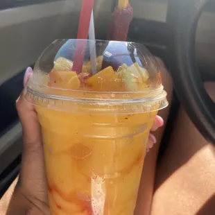 a person holding a cup of fruity drink