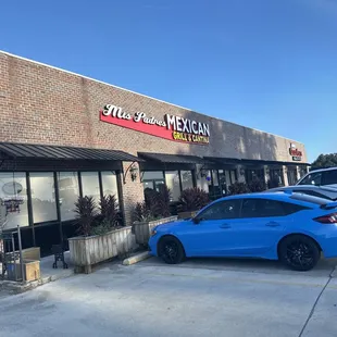 a blue car parked in front of a mexican restaurant