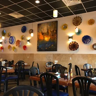 the interior of a restaurant with many plates on the wall