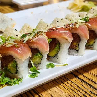 a plate of sushi rolls on a wooden table