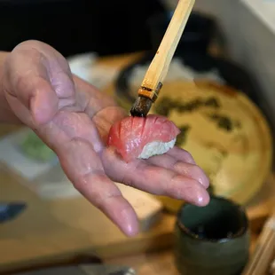 a person holding a piece of sushi in their hand