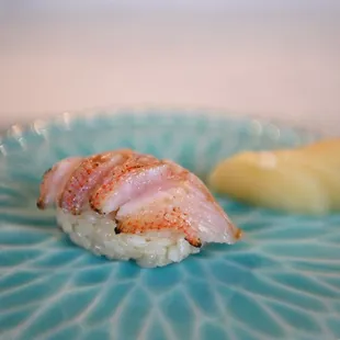 a blue plate with a piece of sushi on it