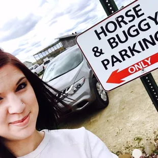 a woman standing in front of a horse and buggy parking sign
