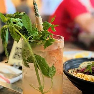 a tall glass of a drink with a straw and a sprig of mint