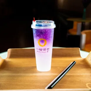 a purple drink and chopsticks on a wooden tray