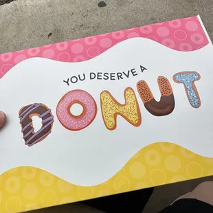 a person holding a box of donuts