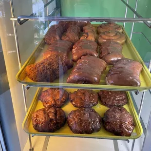 two trays of doughnuts in a display case