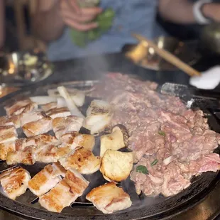 a grill with meat and vegetables cooking on it