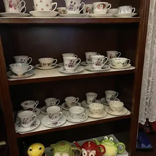 a shelf full of tea cups and saucers