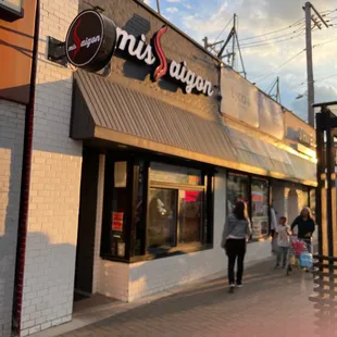 people walking on a sidewalk in front of a restaurant