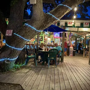 people sitting at tables under a tree