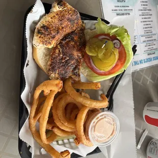 Blackened chicken sandwich with onion rings.