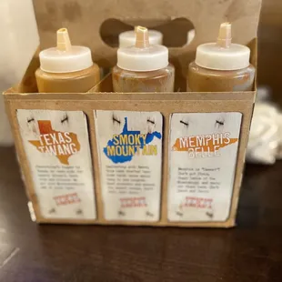 four bottles of bbq sauce in a cardboard box