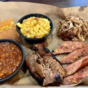 Meat sampler with pulled pork, sausage, and brisket with side orders of baked beans and mac and cheese.