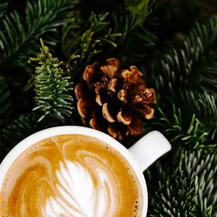 a cup of coffee on a table with pine cones