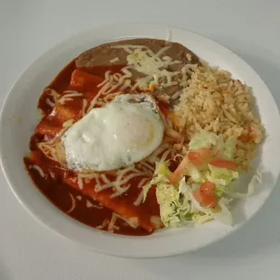 Red enchiladas with egg on top. And rice &amp;  beans