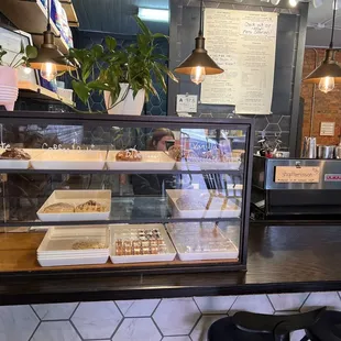 a woman behind the counter of a bakery