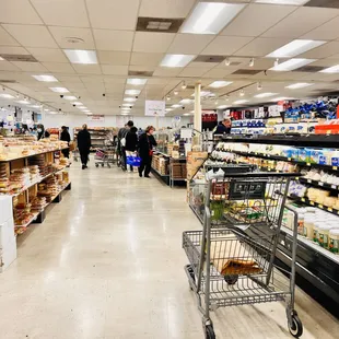 a grocery aisle with a cart full of goods