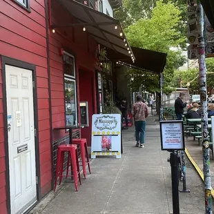 a red building with a sign on the sidewalk