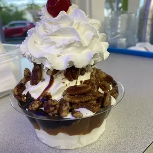 A hot fudge sundae with pecans and whipped cream!