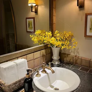a bathroom sink with yellow flowers in a vase