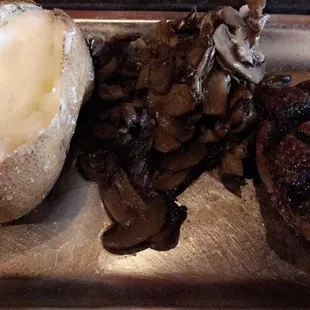 The filet cooked medium well with a baked potato and sautéed mushrooms.