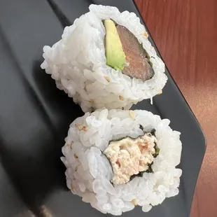 two sushi rolls on a black plate