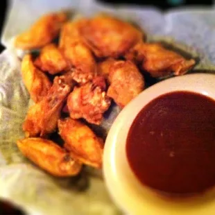 a plate of chicken wings and a bowl of sauce