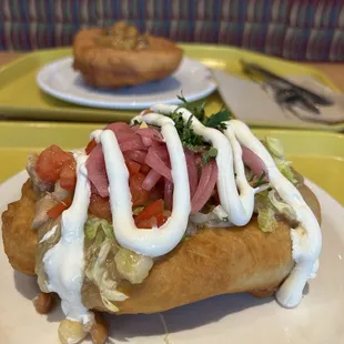 Fry bread taco with turkey chili. Includes all toppings except the jalapeño.   Apple fry bread in the background.