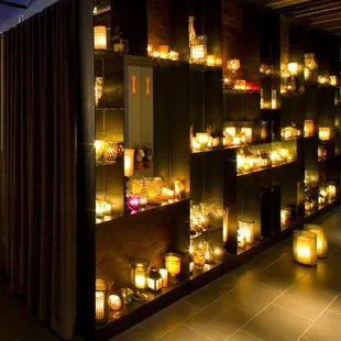 a wall of candles in a dimly lit room