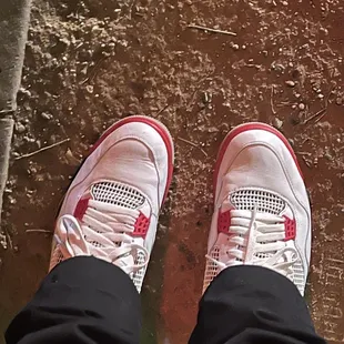 a person's feet in white and red sneakers