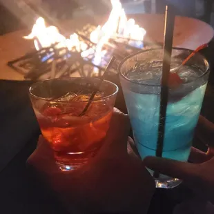two cocktails in front of a fire