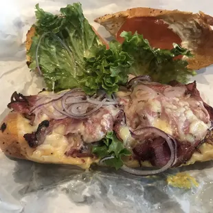 Pastrami on onion roll with the works inside