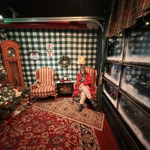 a woman sitting in a chair in front of a christmas tree