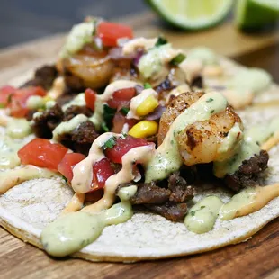 Surf &apos;N&apos; Turf Taco
Corn of flour tortillas, with carne asada, cilantro-lime shrimp, pico de gallo, chipotle tartar &amp; serrano aioli sauce.