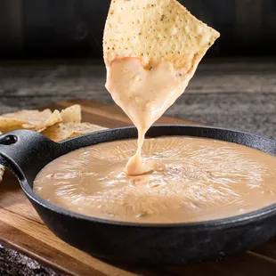 a tortilla being dipped with cheese