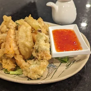 a plate of fried vegetables and dipping sauce