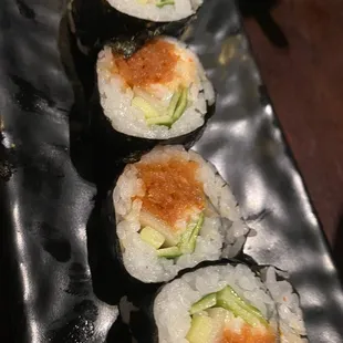a row of sushi rolls on a black plate
