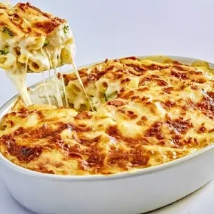 a fork lifting a piece of cheese from a casserole dish