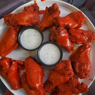 a plate of buffalo wings with ranched dips