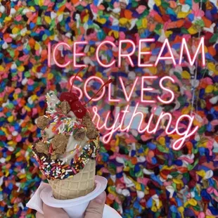 Small coconut in a dipped cone with sprinkles, cookie dough, and cherries.