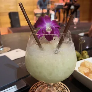 a cocktail with a purple flower