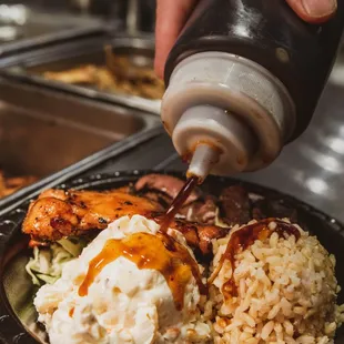 person pouring ketchup onto a plate of food