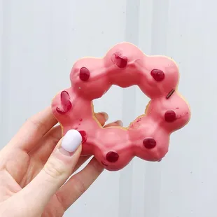 a hand holding a pink donut